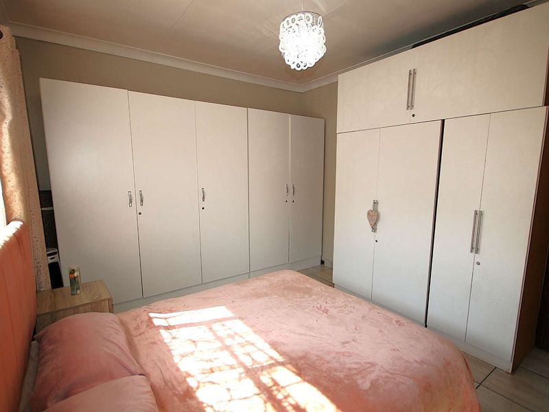 A bedroom featuring extensive white built-in cupboards providing ample storage space and tiled flooring.