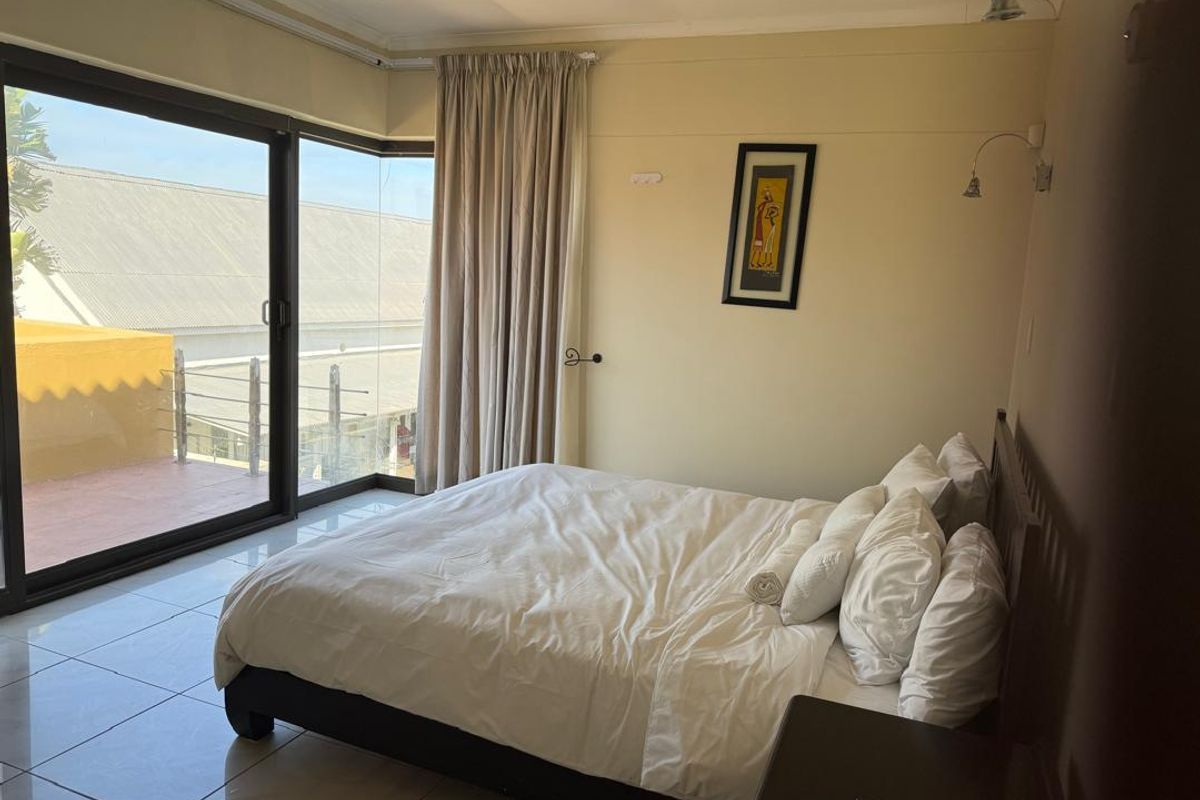 A bedroom featuring large sliding glass doors that open onto a balcony, providing natural light and access to outdoor space.