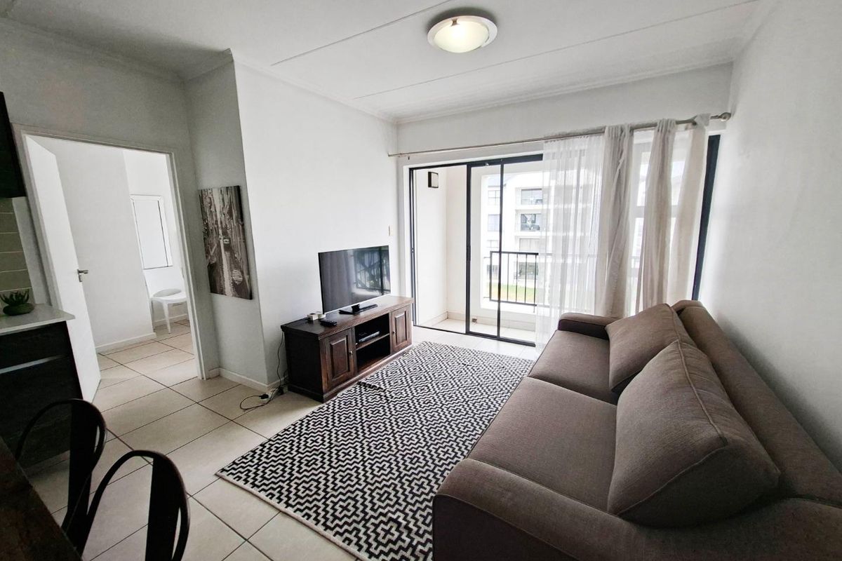 A bright living room featuring tiled flooring and a sliding glass door providing access to a private balcony.