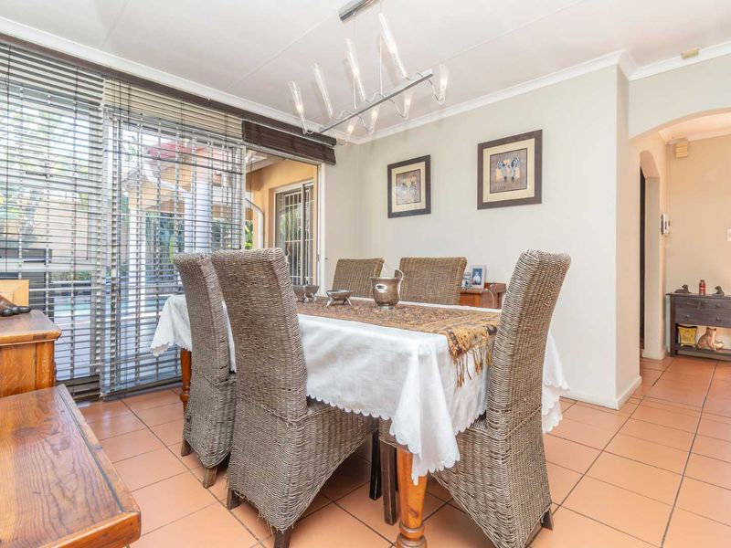 A bright dining room featuring tiled flooring, a modern light fixture, and large sliding glass doors that provide access to the outdoor patio area.