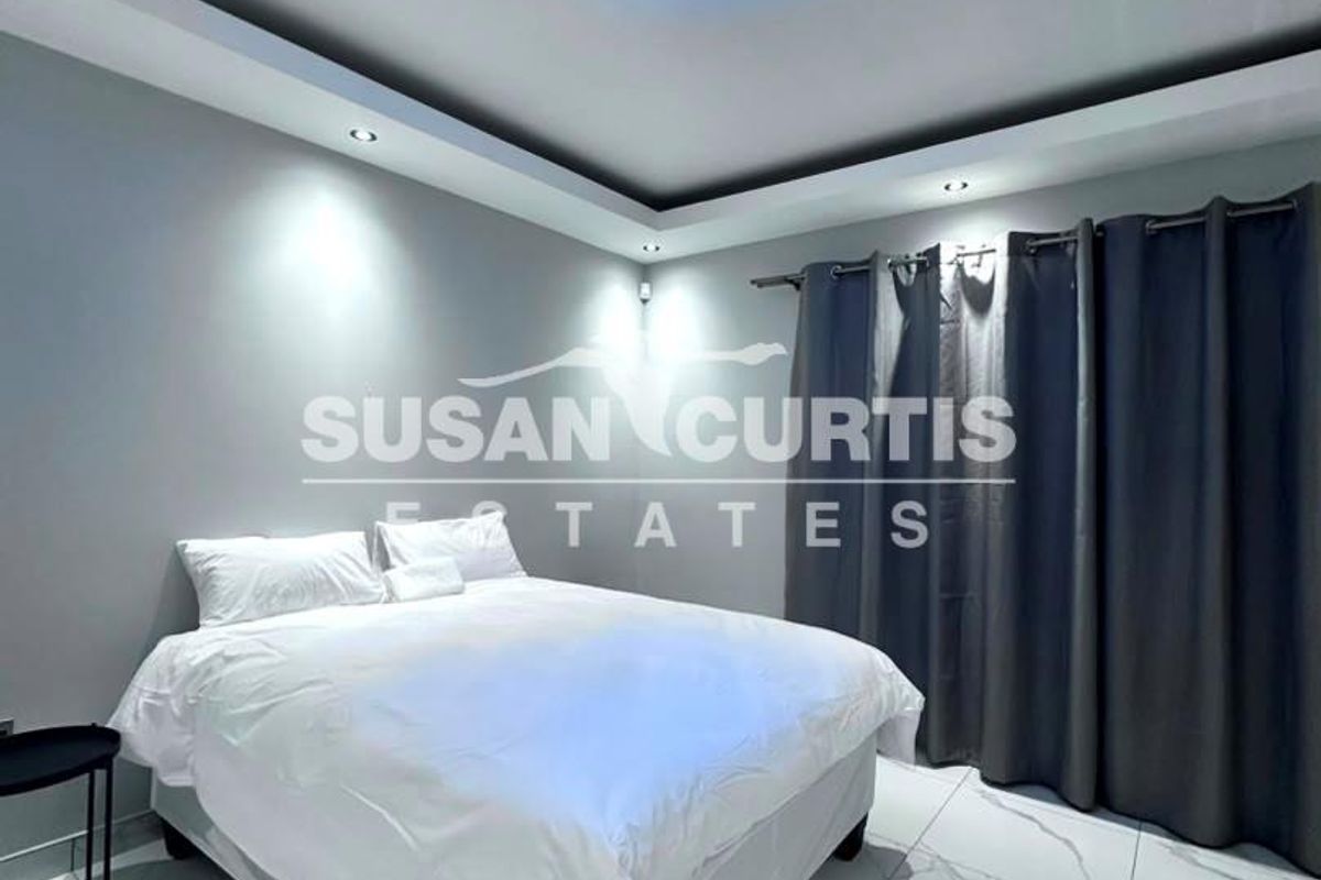 Modern bedroom featuring large format marble-look floor tiles, recessed ceiling lighting, and a contemporary blue crystal flush-mount light fixture.