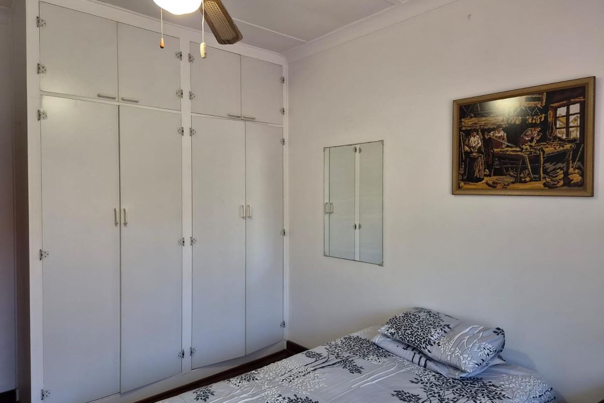 A bedroom featuring floor-to-ceiling built-in cupboards and a ceiling fan, offering functional storage space.