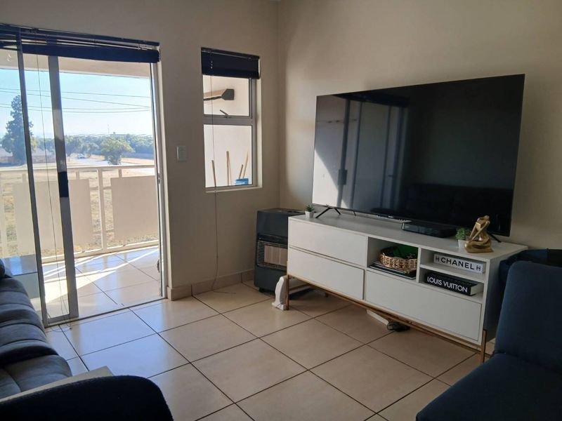 A living room featuring tiled flooring, a gas heater, and a sliding glass door providing access to an outdoor balcony area.