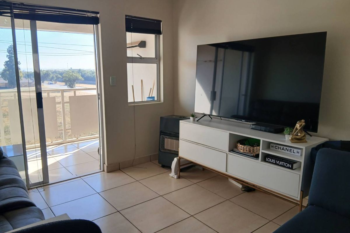 A living room featuring tiled flooring, a gas heater, and a sliding glass door providing access to an outdoor balcony area.