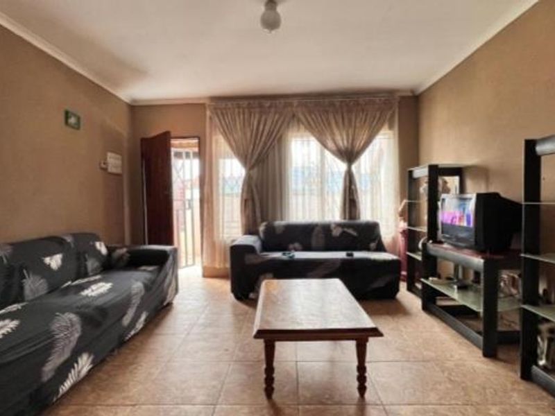 A living room featuring tiled flooring and a security gate, providing a functional and accessible space for relaxation.