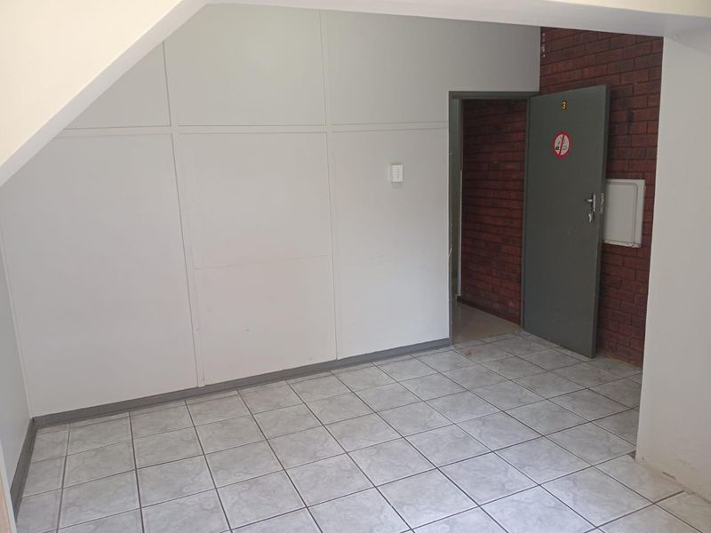 A vacant entry area featuring tiled flooring, a combination of panelled and exposed brick walls, and a single internal access door.