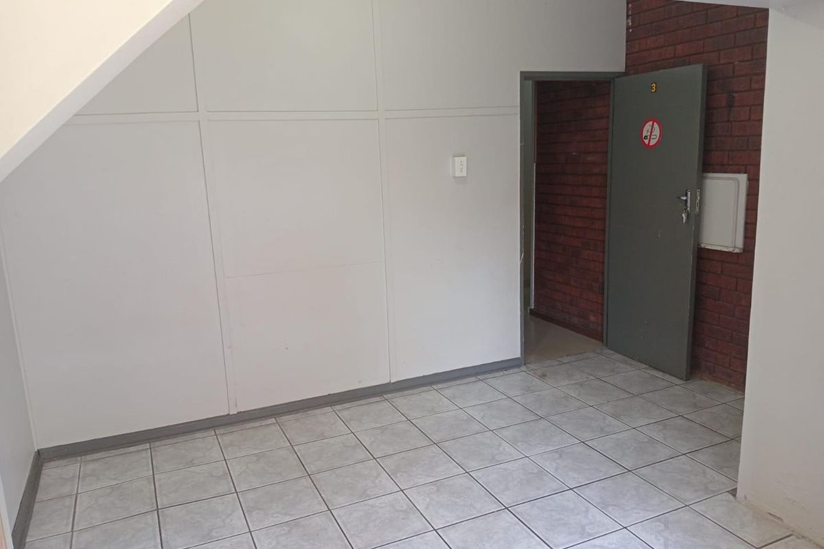 A vacant entry area featuring tiled flooring, a combination of panelled and exposed brick walls, and a single internal access door.