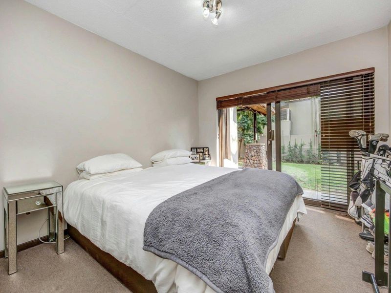 A bedroom featuring neutral walls, carpeted flooring, and a sliding glass door providing direct access to the garden area.