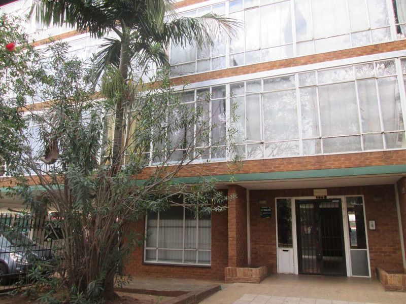 Front elevation of a multi-story apartment building featuring a brick facade, large glass window panels, and a secure entrance area.