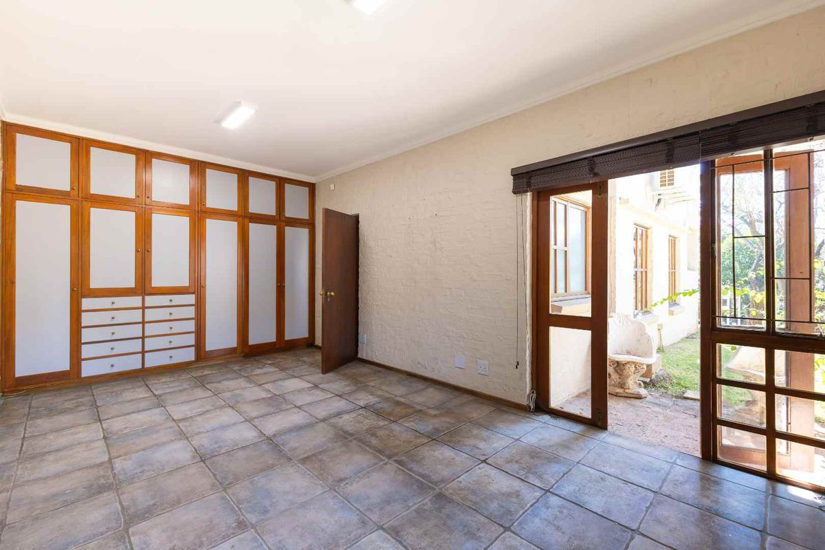 Spacious bedroom featuring built-in cupboards, tiled flooring, and direct access to an outdoor area through a sliding door.