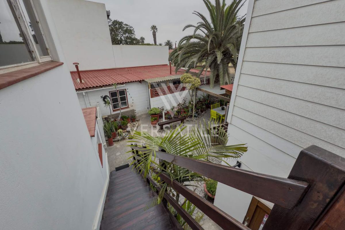 View from an elevated timber staircase looking down into a paved rear courtyard area with surrounding building structures.