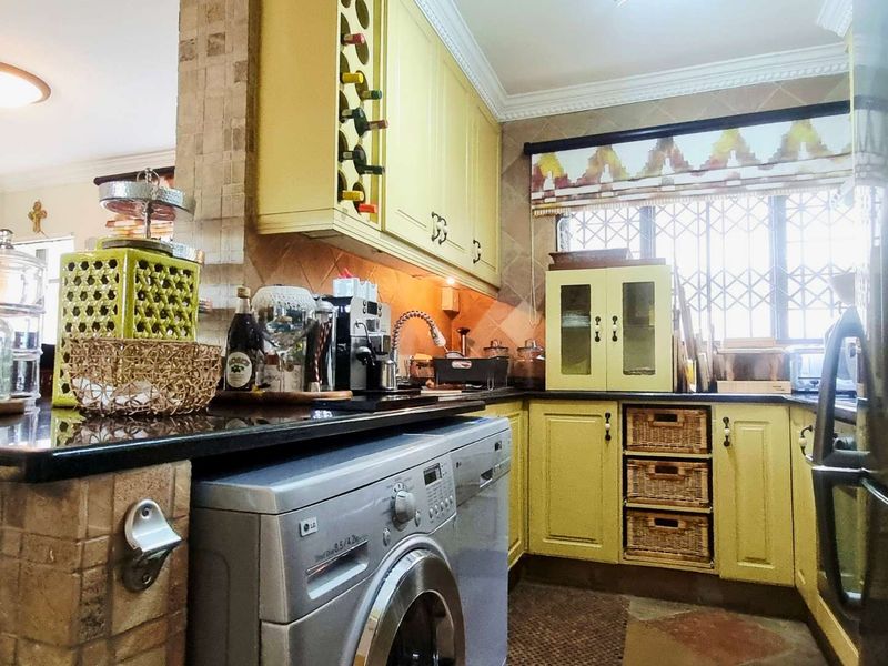 A functional kitchen featuring yellow cabinetry, granite countertops, tiled backsplash, and integrated storage solutions, offering a warm and practical cooking space.