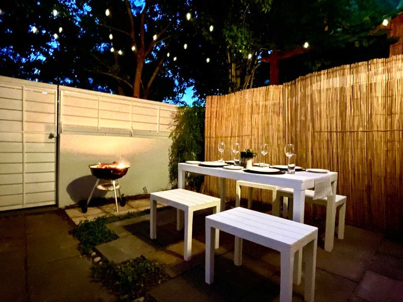 An outdoor patio area featuring paved flooring and bamboo privacy fencing, suitable for evening dining and entertainment.