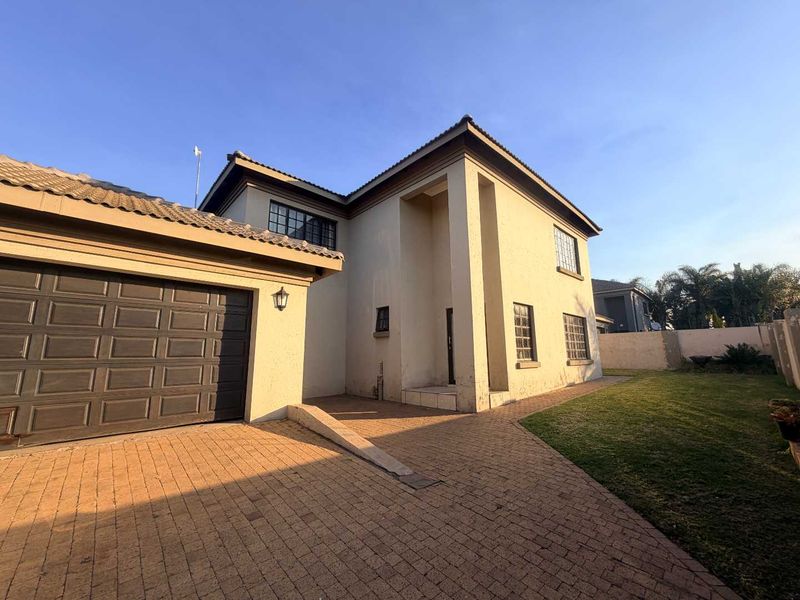 Front view of a two-story residential house featuring a paved driveway, double garage, and a well-maintained lawn area.