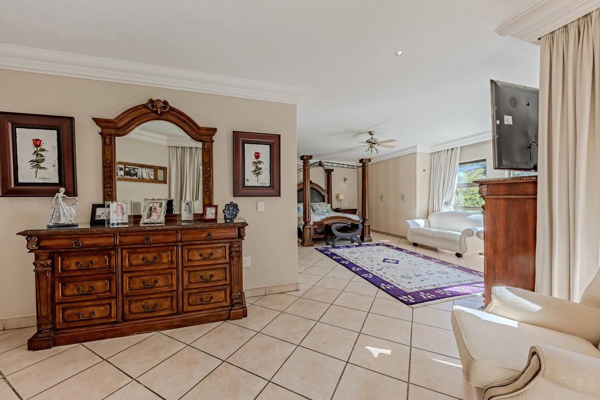 Spacious bedroom featuring tiled flooring, built-in cupboards, and a ceiling fan, offering a comfortable and well-maintained living space.