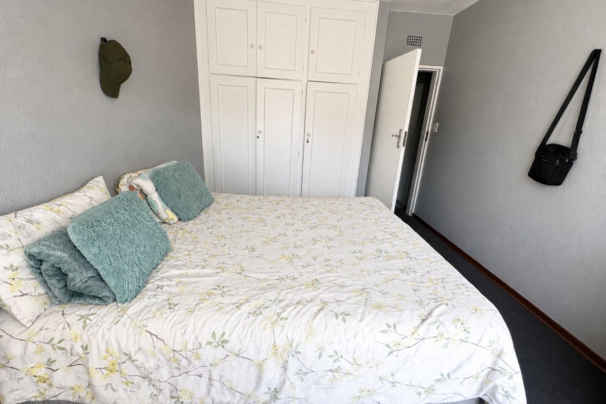 A functional bedroom featuring built-in cupboards and neutral wall finishes, providing a clean and practical space.