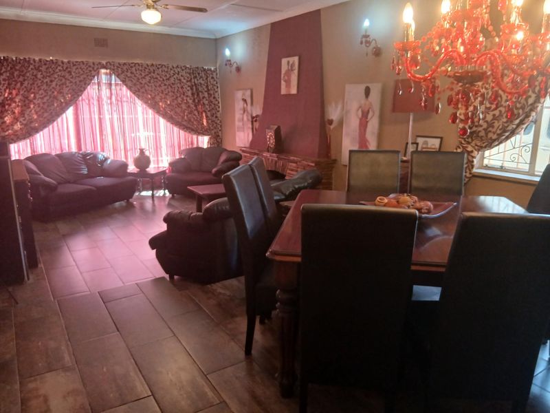 Spacious open-plan living and dining area featuring tiled flooring, a central fireplace, and a ceiling fan, offering a versatile layout for family living.