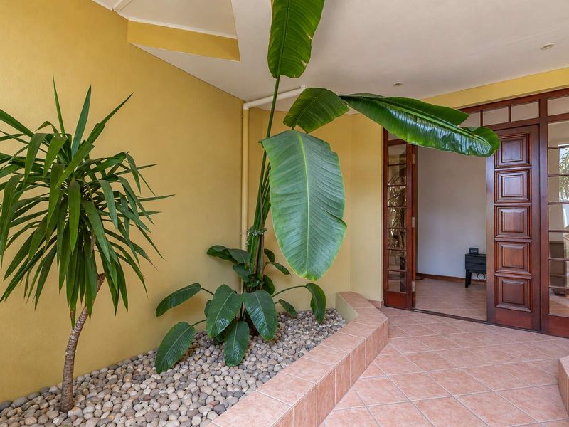 A welcoming entrance area featuring tiled flooring, a timber-framed glass door, and a built-in planter box with decorative stone.