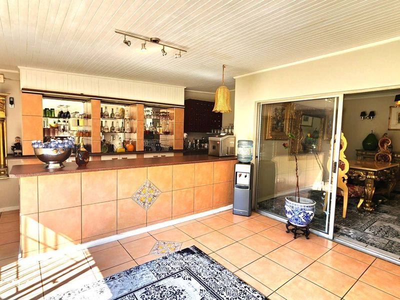 A dedicated bar area featuring a tiled counter, built-in shelving, and direct access to the dining room through sliding glass doors.