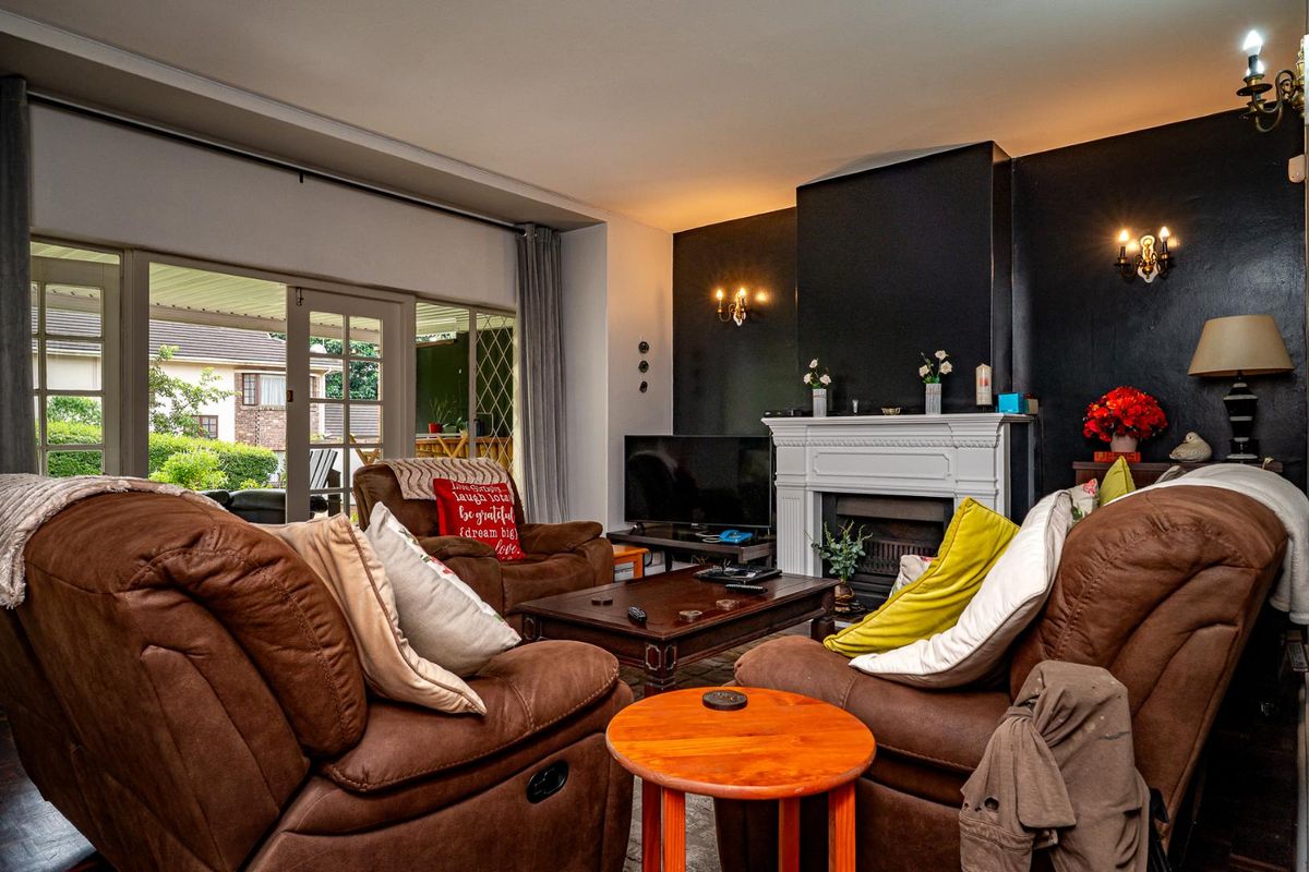 Spacious living room featuring a classic white fireplace mantel, dark accent wall, and sliding glass doors providing direct access to the outdoor patio area.