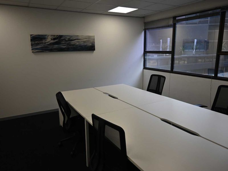 A functional office space featuring a suspended ceiling, recessed lighting, and large windows providing natural light.