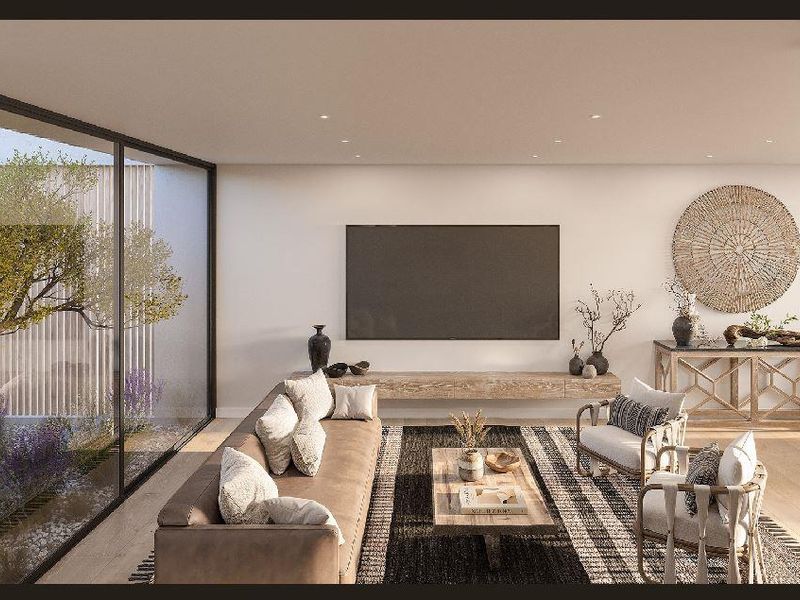 Modern open-plan living area featuring large floor-to-ceiling sliding glass doors overlooking a private courtyard, recessed lighting, and a sleek floating media console.