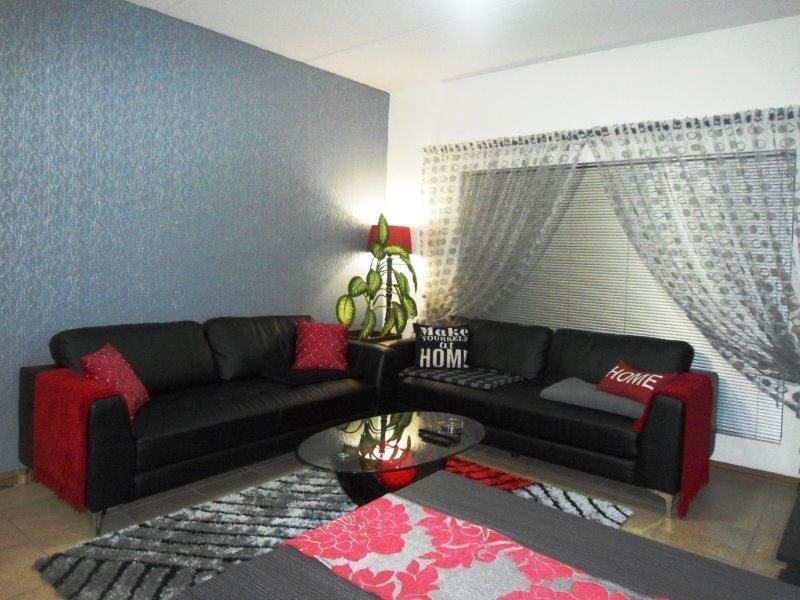 A comfortable living room featuring tiled flooring, a textured feature wall, and venetian blinds for privacy.