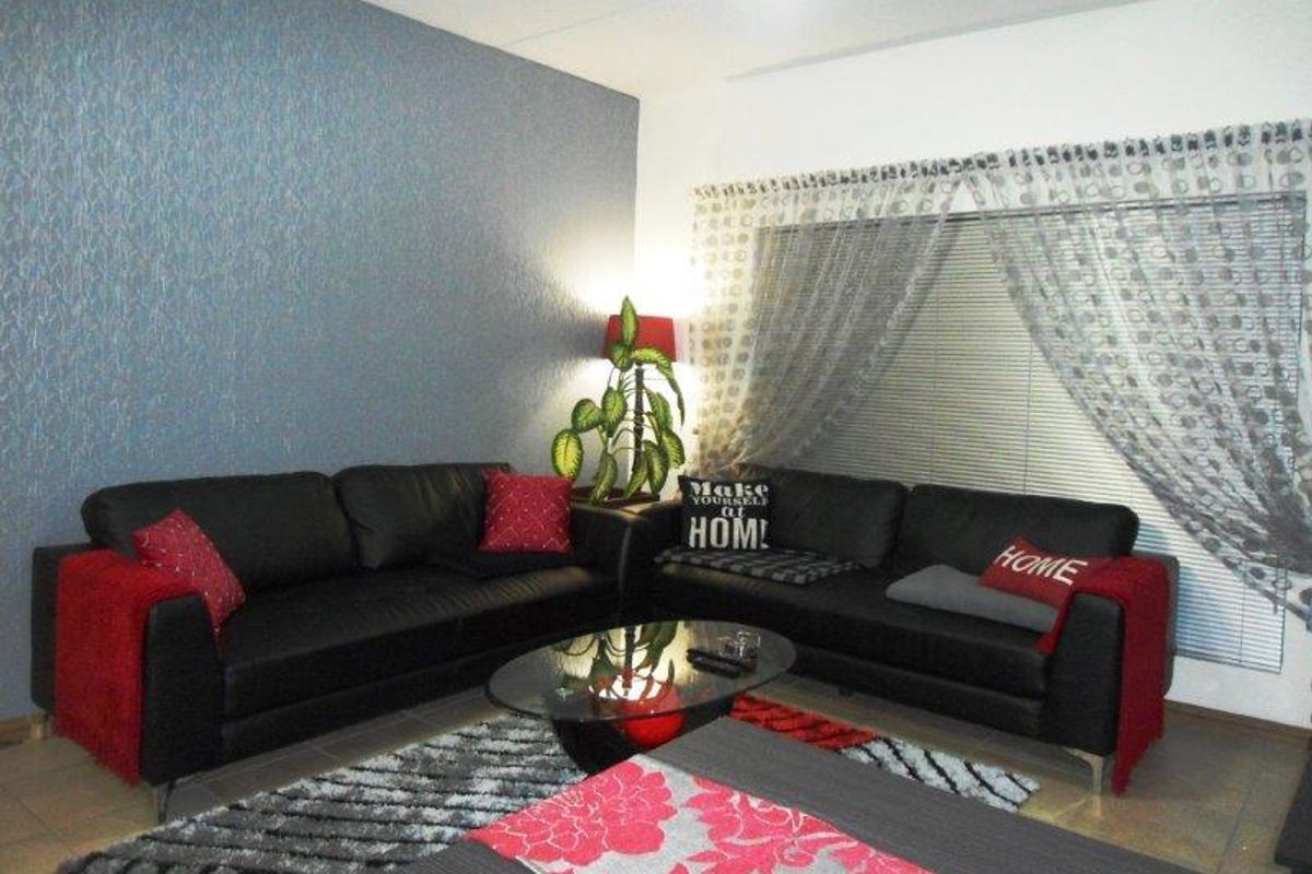 A comfortable living room featuring tiled flooring, a textured feature wall, and venetian blinds for privacy.