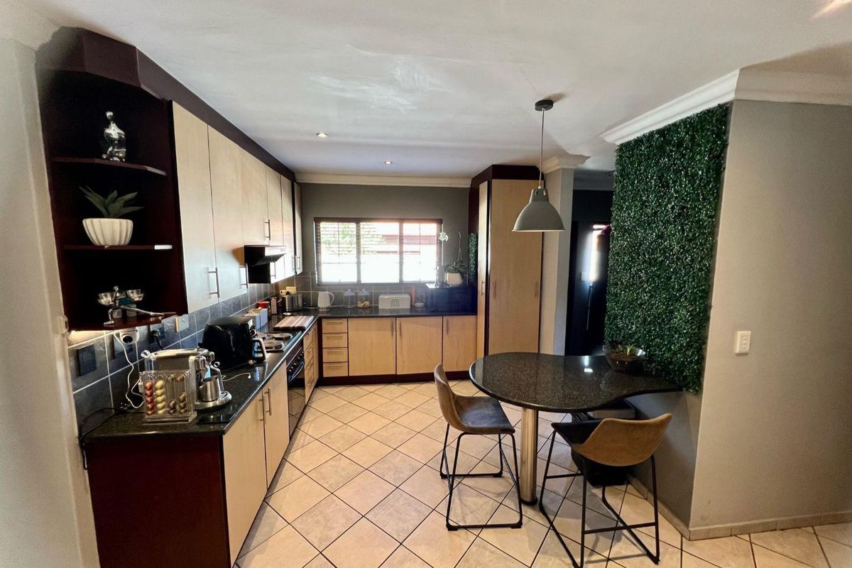 A functional kitchen featuring light wood cabinetry, dark granite countertops, tiled flooring, and a built-in breakfast nook with integrated lighting.