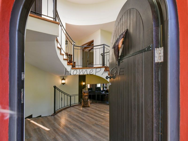 Grand entrance foyer featuring a striking curved staircase with wrought iron balustrades and elegant timber flooring, creating a welcoming and spacious architectural focal point.