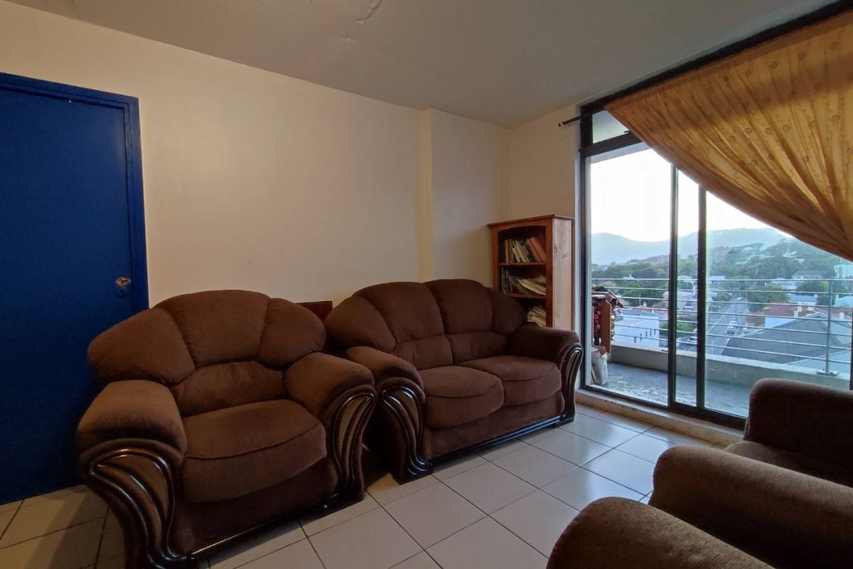 A living room featuring tiled flooring, a blue interior door, and large sliding glass doors leading to a balcony with mountain views.