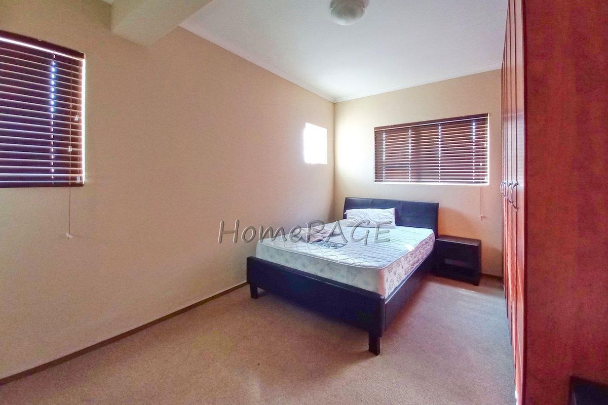 A bedroom featuring built-in wooden cupboards, carpeted flooring, and venetian blinds on the windows.