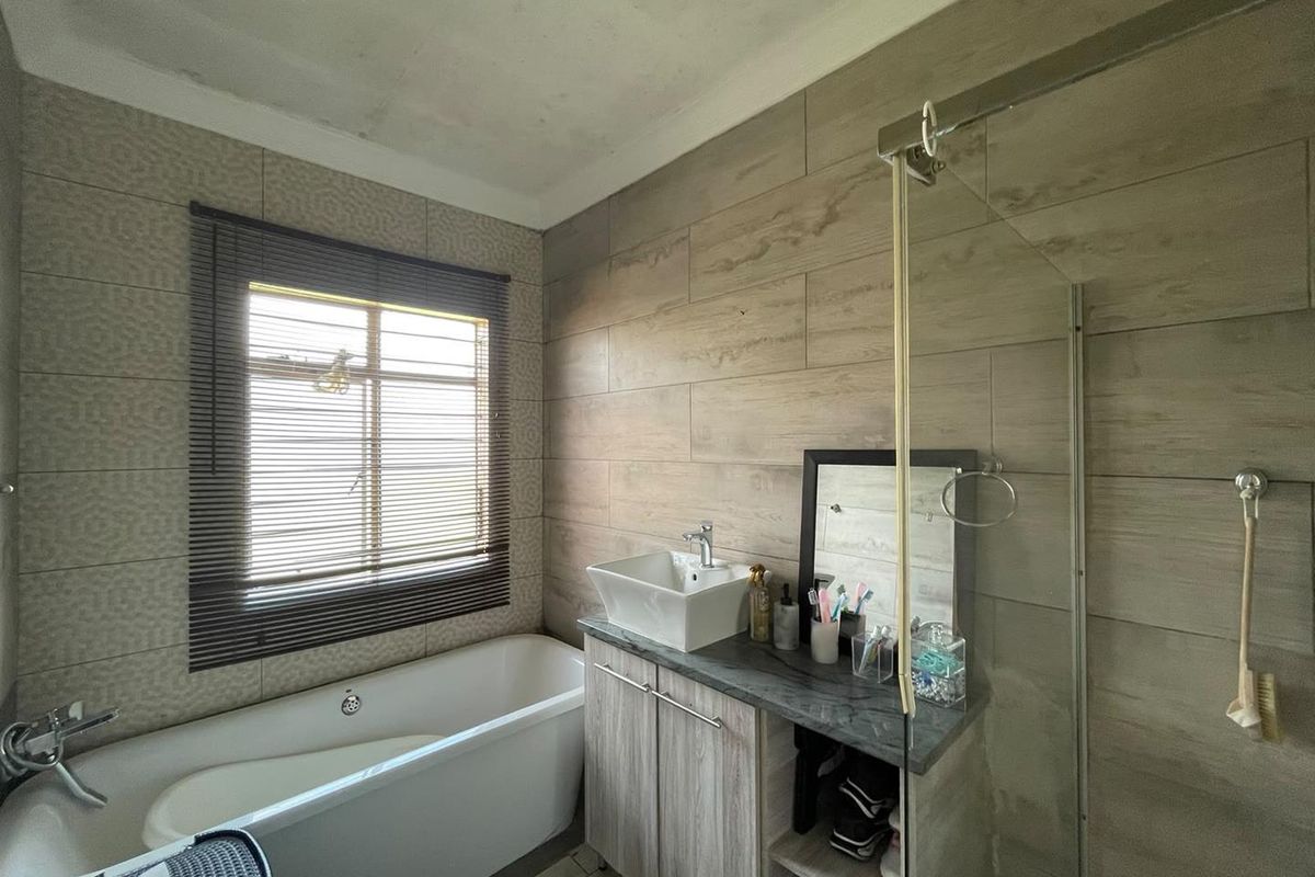 Modern bathroom featuring a freestanding bathtub, vessel sink vanity, and glass-enclosed shower with wood-look wall tiling.