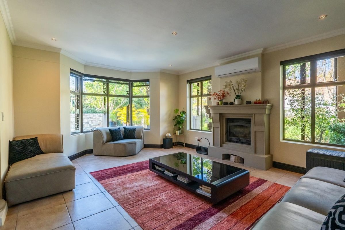Spacious living room featuring a built-in fireplace, large bay windows, tiled flooring, and a wall-mounted air conditioning unit.