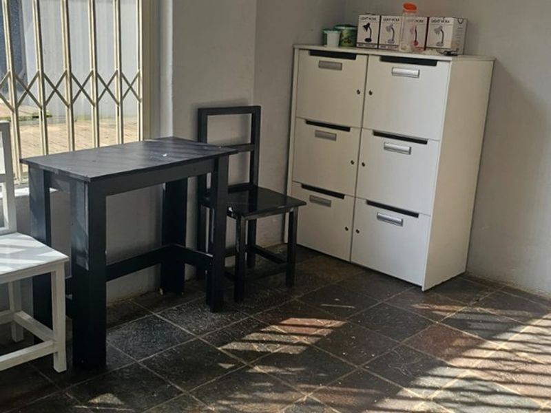 A utility space featuring stone tile flooring and a security gate, suitable for use as a home office or storage area.