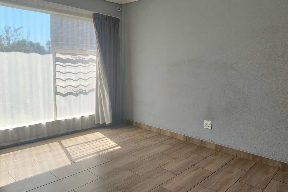 A vacant bedroom featuring wood-look tiled flooring, a large window for natural light, and neutral wall finishes.