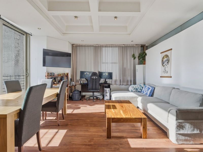 Spacious open-plan living and dining area featuring a coffered ceiling, recessed lighting, and durable laminate flooring with access to an outdoor balcony.