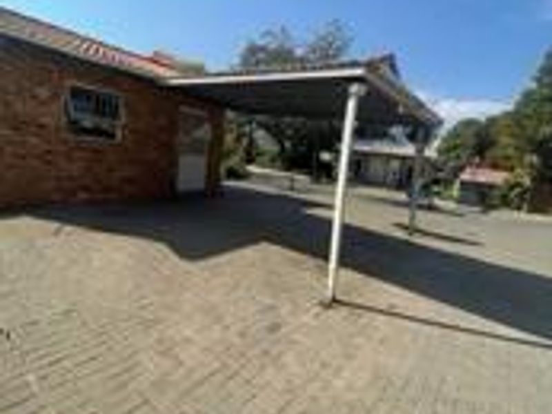 Exterior view of a brick cluster home featuring a paved driveway and a covered carport area.