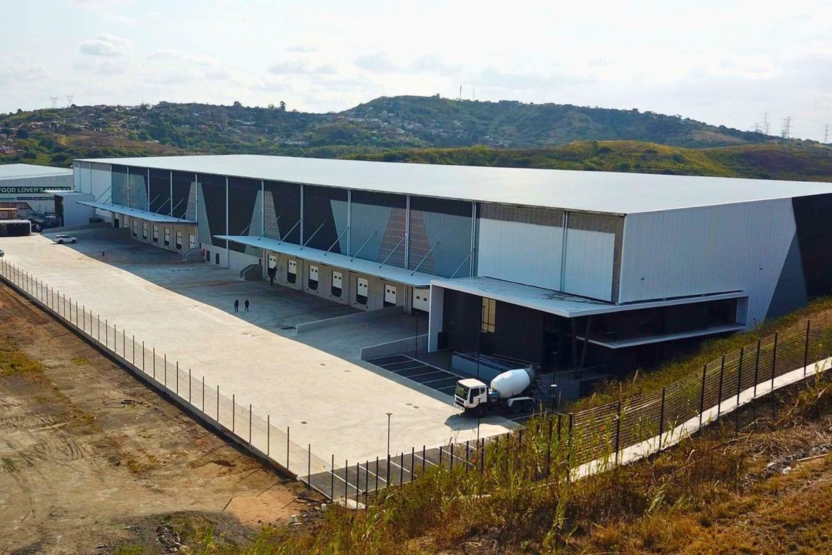 Aerial view of a large industrial warehouse facility featuring multiple loading docks, extensive concrete yard space, and secure perimeter fencing.