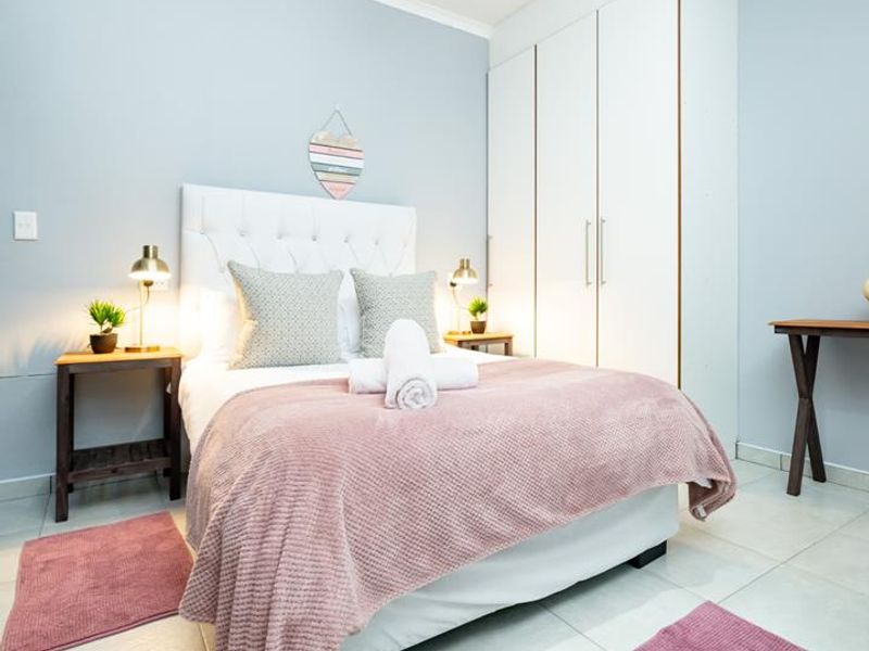 A well-maintained bedroom featuring light-toned tiled flooring, a built-in wardrobe with white cabinetry, and neutral wall finishes.