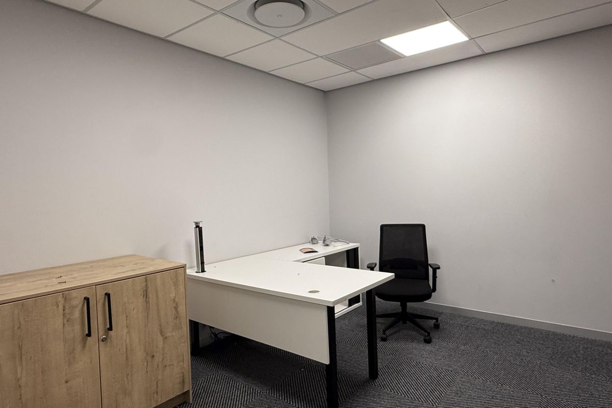 A clean, professional office space featuring a suspended ceiling, recessed lighting, and modern carpeted flooring, suitable for a productive work environment.