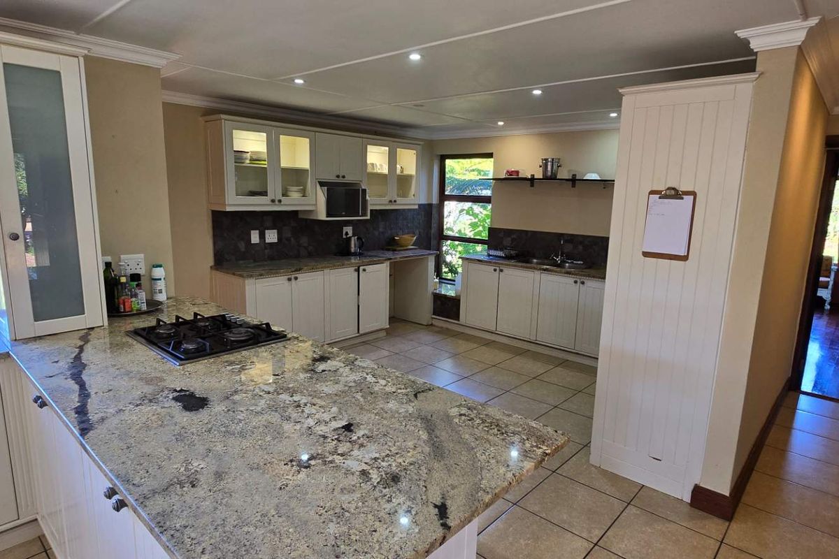 A well-appointed kitchen featuring granite countertops, built-in cabinetry, a gas hob, and recessed ceiling lighting, offering a functional and bright workspace.