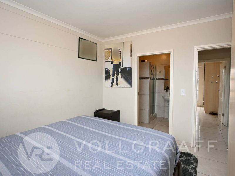 A bedroom featuring tiled flooring, built-in wardrobes, and direct access to an en-suite bathroom.