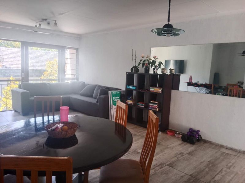 Open plan living and dining area featuring tiled flooring, a large wall mirror, and sliding glass doors leading to an outdoor space.