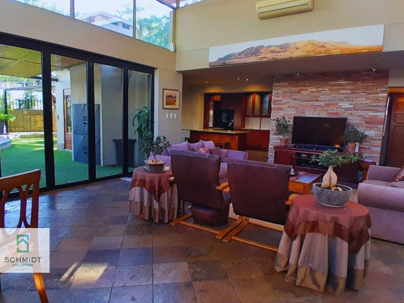 Spacious open-plan living area featuring high ceilings, stone-clad feature wall, and large sliding glass doors providing seamless access to the outdoor patio.