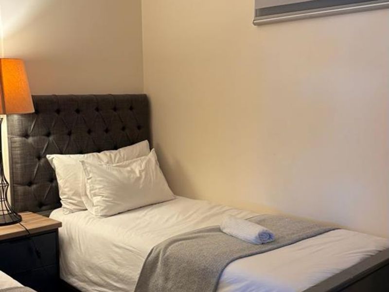 A compact bedroom featuring neutral wall finishes and a modern roller blind, providing a functional sleeping space.