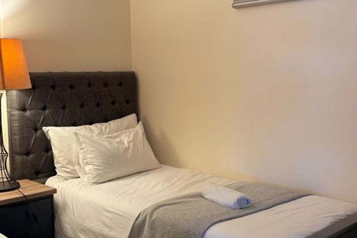 A compact bedroom featuring neutral wall finishes and a modern roller blind, providing a functional sleeping space.