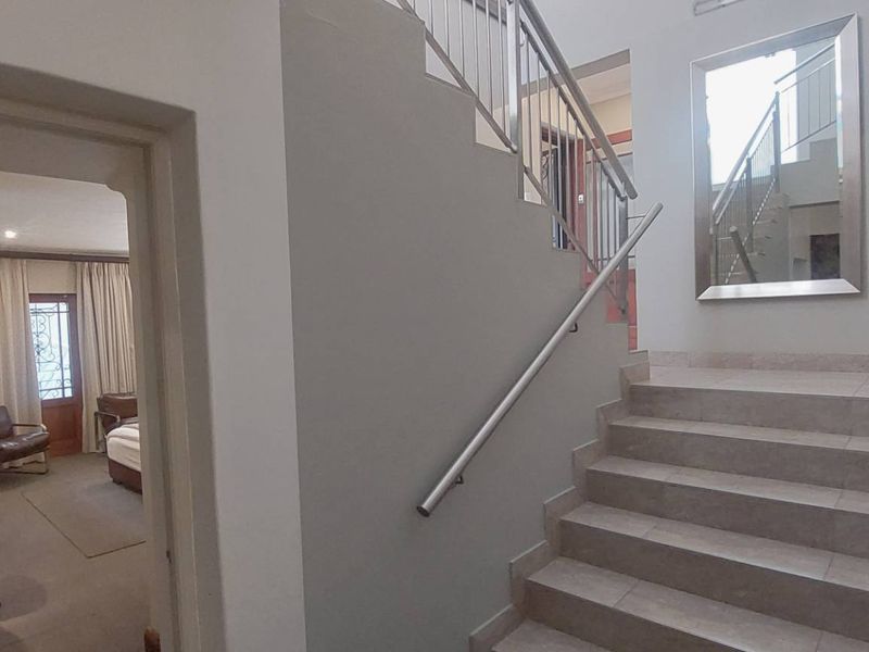 A bright hallway featuring a tiled staircase with a modern metal handrail, providing access to the upper level of the townhouse.