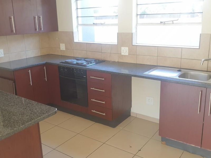 A functional kitchen featuring dark wood cabinetry, granite countertops, a built-in oven and hob, and a double sink with tiled backsplash.
