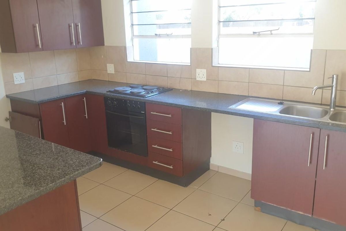 A functional kitchen featuring dark wood cabinetry, granite countertops, a built-in oven and hob, and a double sink with tiled backsplash.